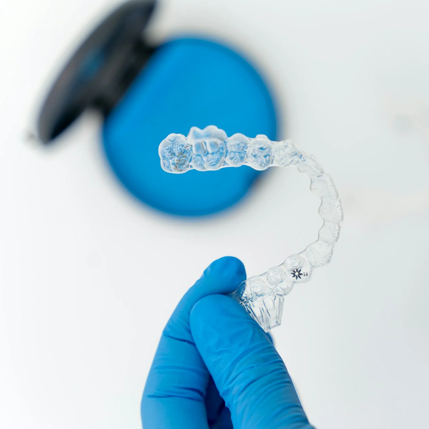 A clinician holding a clear Invisalign aligner